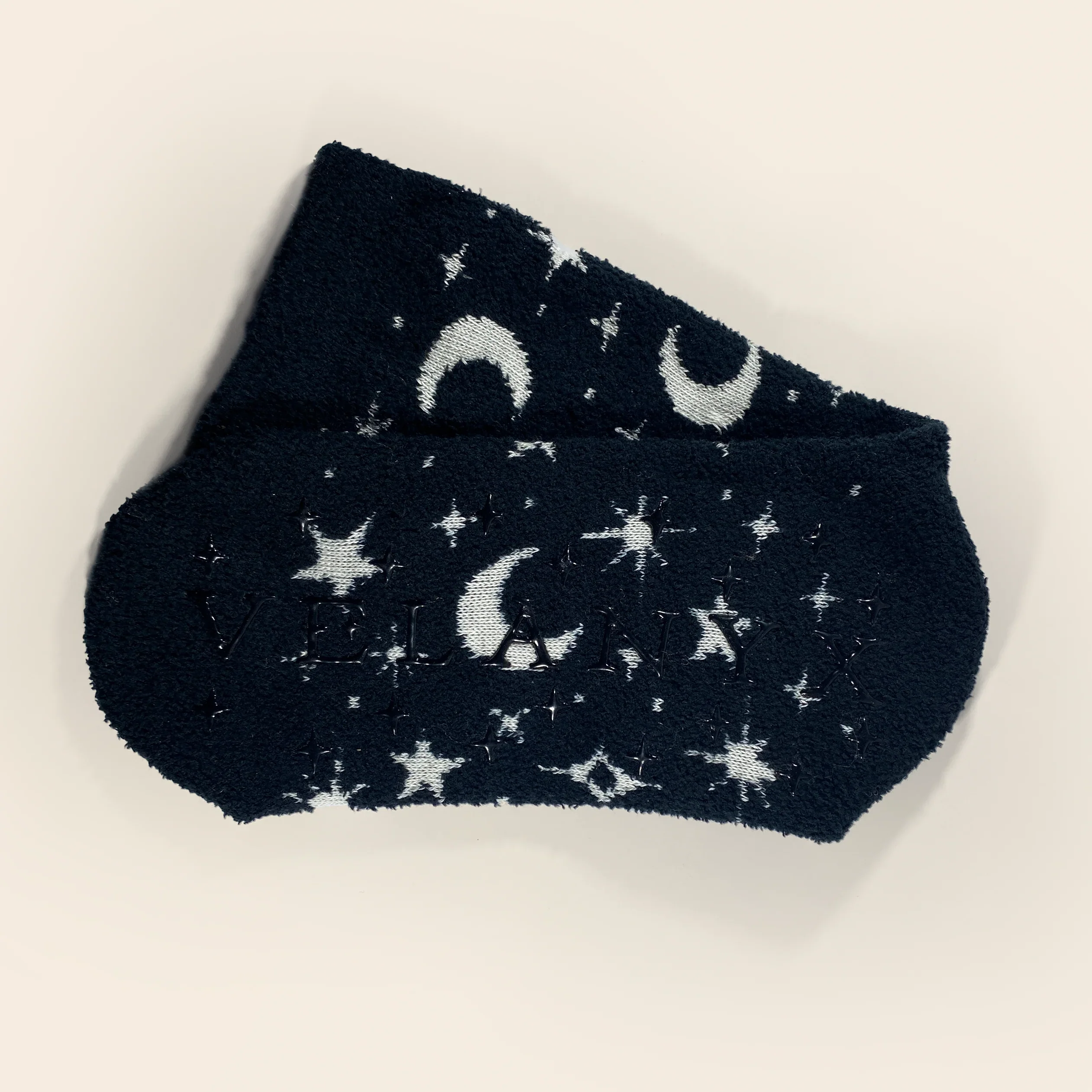 Pair of dark blue socks with white star and moon patterns on a light 
Celestial glow-in-the-dark cozy socks with star and moon pattern by Velanyx

Soft plush gripper socks that glow in the dark in celestial design

Black cozy socks with glow star pattern and non-slip bottoms

Witchy celestial glow socks perfect for cozy nights and gifting

Velanyx glow-in-the-dark star socks ultra soft plush materialbackground